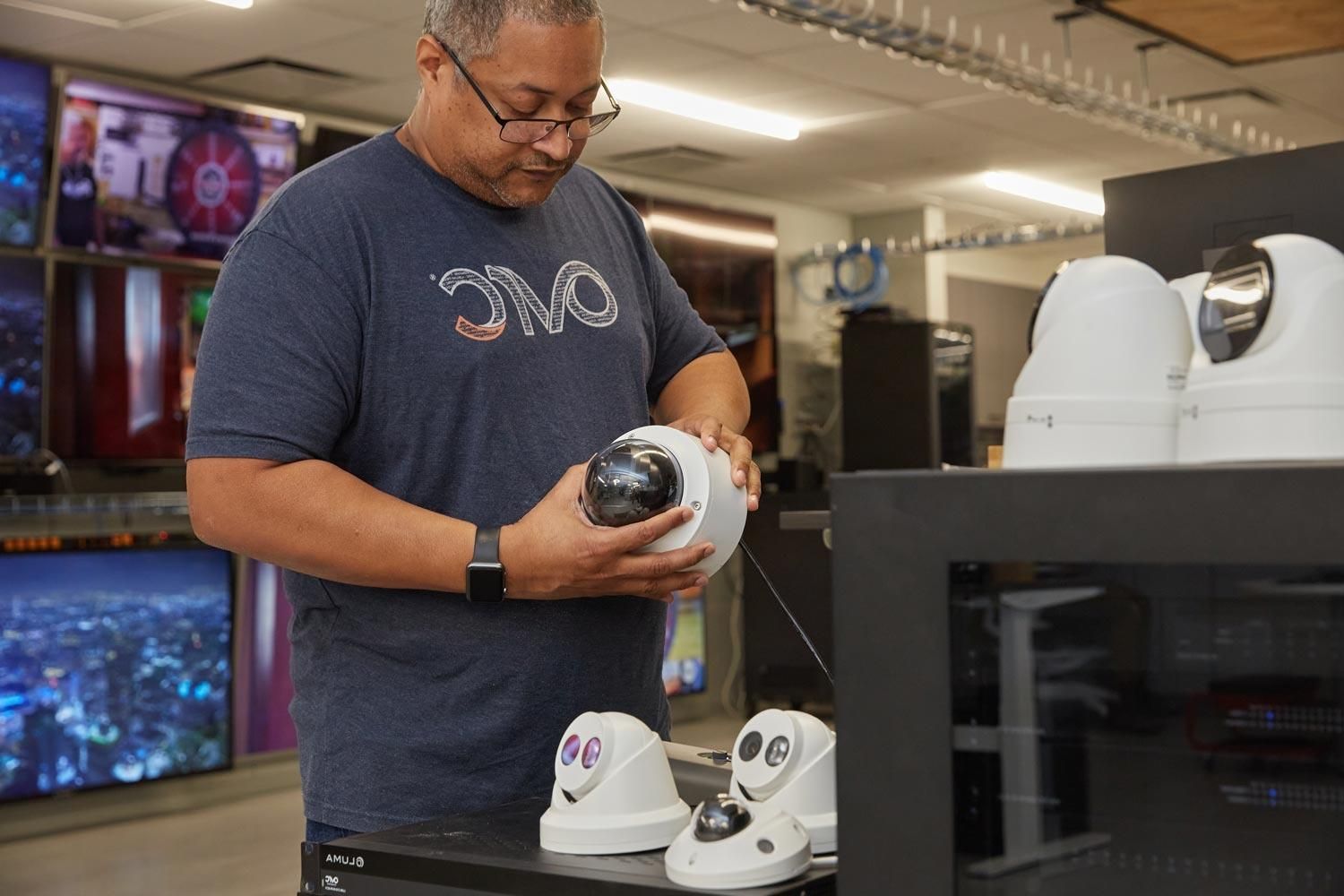 Technician inspecting and preparing security cameras for installation in a control room.