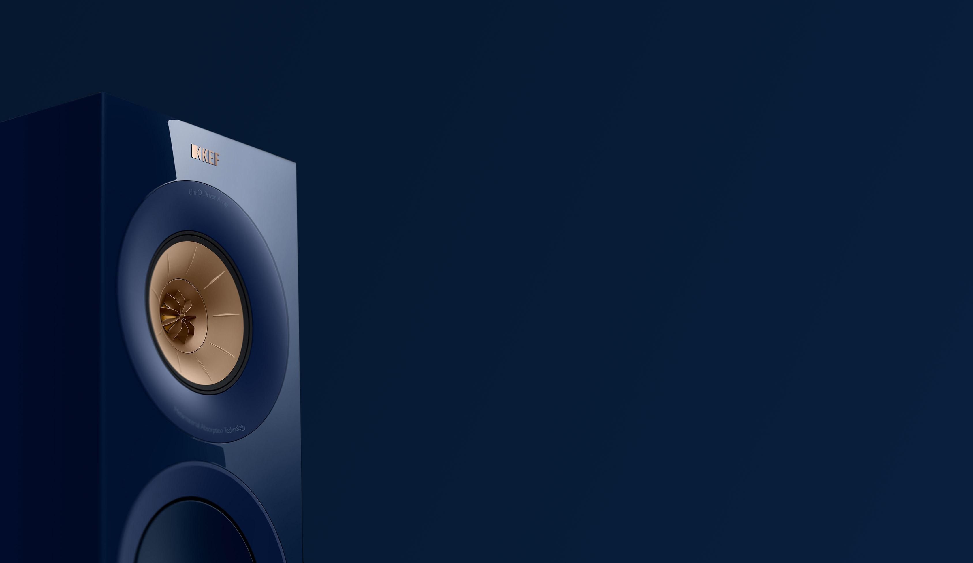 A close-up view of a blue KEF HiFi speaker featuring a gold Uni-Q driver array against a dark blue background.