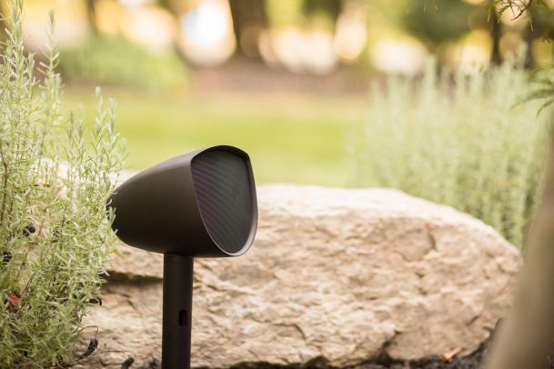 Outdoor speaker blending into the landscape, surrounded by greenery.