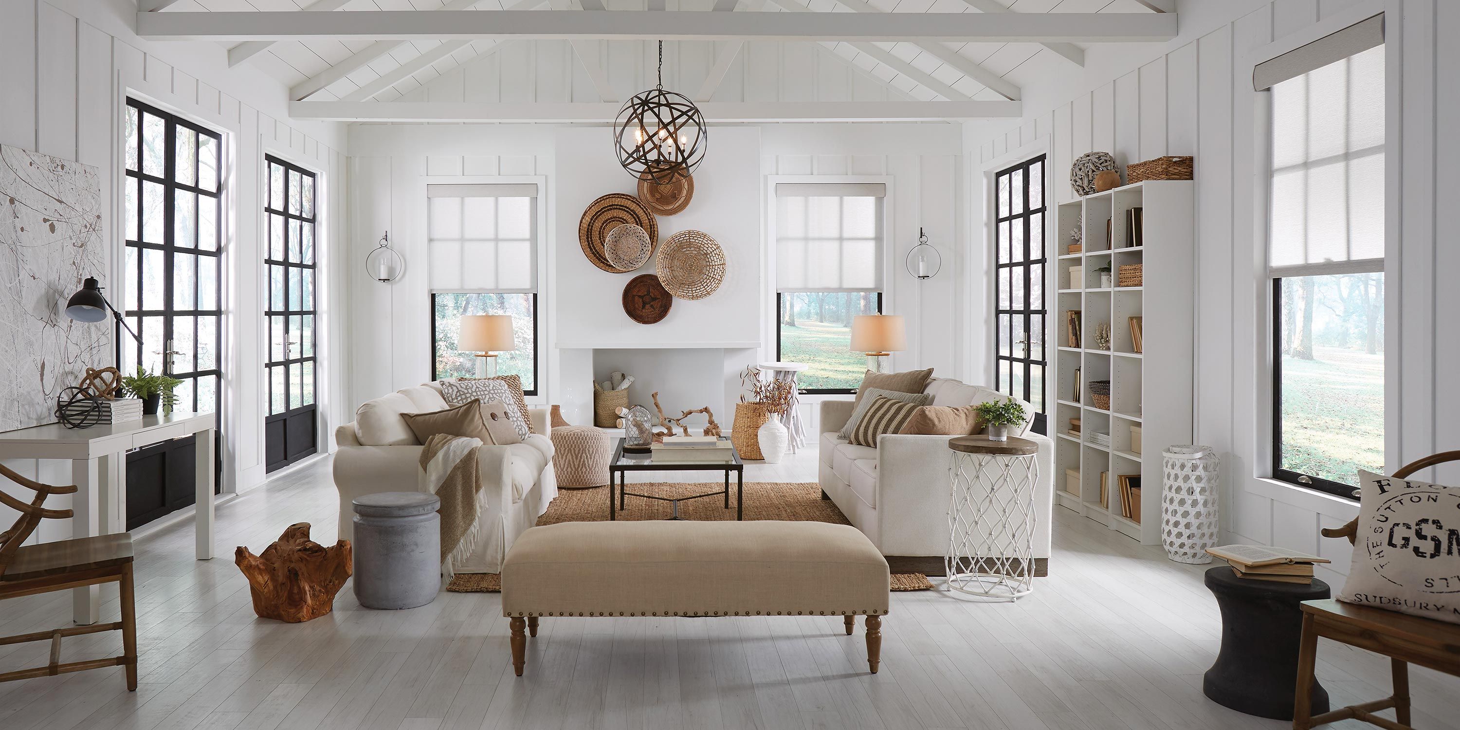 Airy living space with rustic decor, featuring white walls, large windows, and comfortable seating.