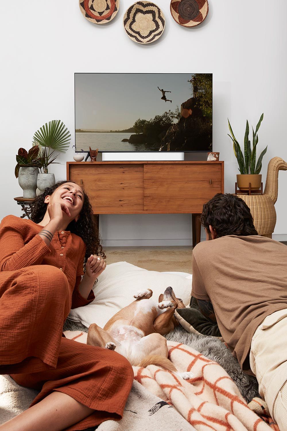 Man, woman and dog on the floor. On the back Sonos arc bar with TV