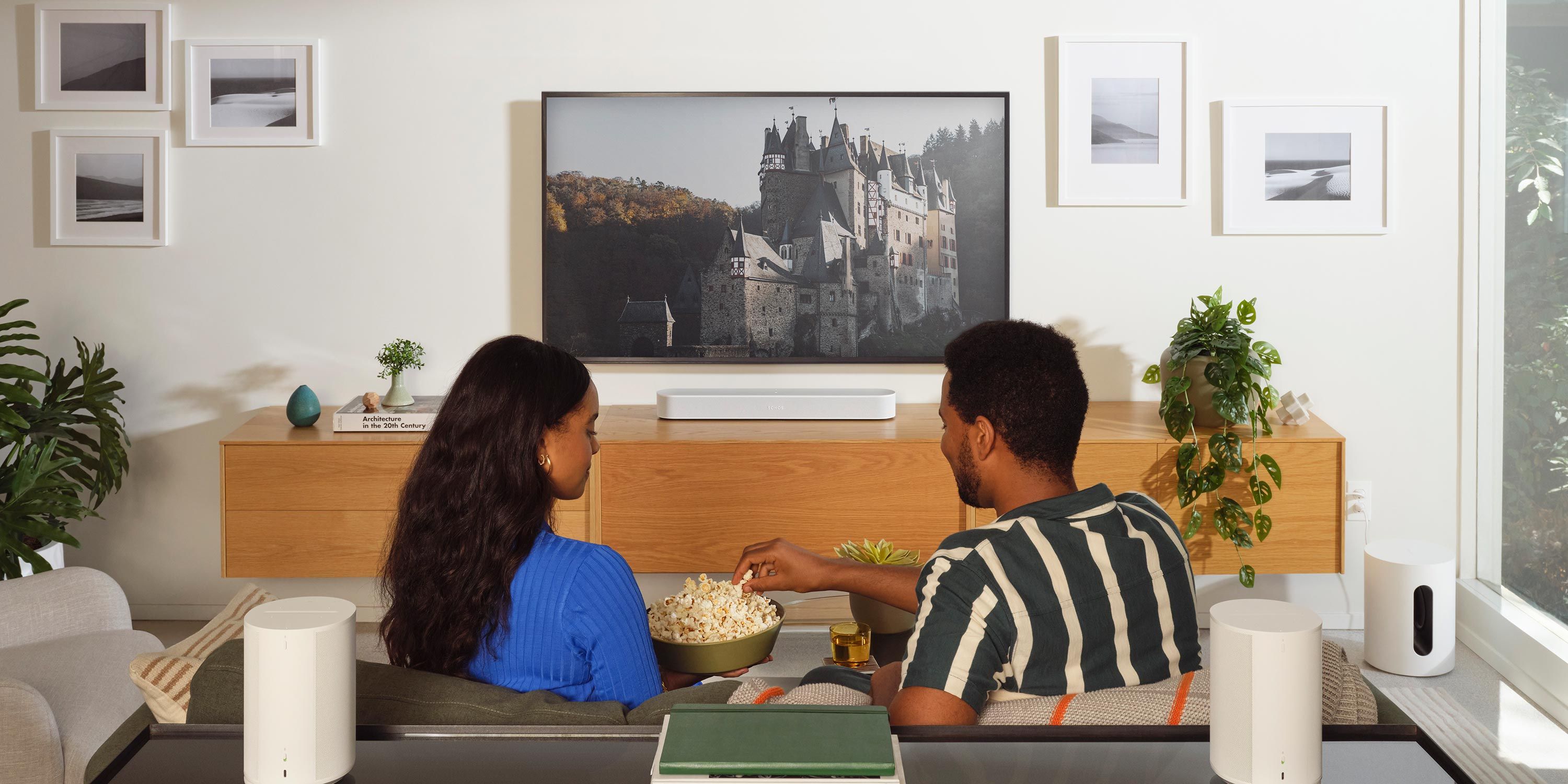 Couple enjoying a movie in a cozy media room with a minimalist design and sound equipment.